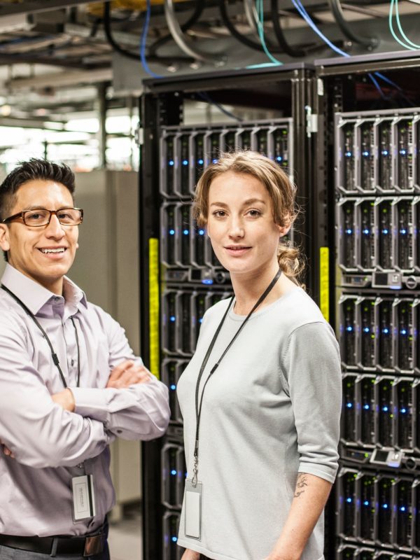 Caucasian man and woman technicians in a large computer server farm.